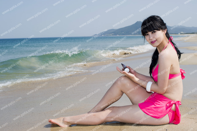 해변가에 비키니 여성이 썬크림들고 있는 모습 이미지 미리보기